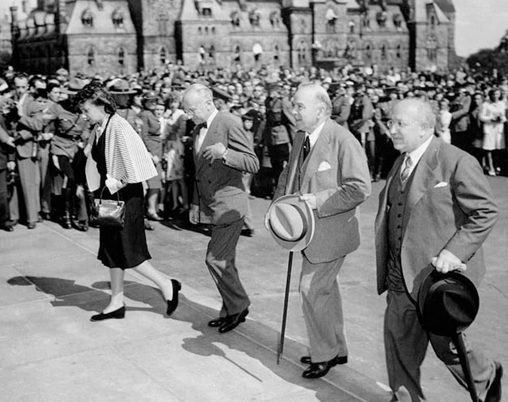 Prime Minister Mackenzie King observes Victory in Japan Day alongside the Minister to Canada from the Argentine Republic and his wife, and the Minister to Canada from the Czechoslovakian Republic. VJ Day marked not only the end of the war in the Pacific Theatre, but also meant that Canadian prisoners of war held in terrible conditions by the Japanese could finally return home. Also released were the surviving Canadian soldiers who were captured in the attacks on Hong Kong after being held for almost five years. Japanese POW camps were notoriously inhumane, and were among the worst of those Canadian prisoners endured during World War II.