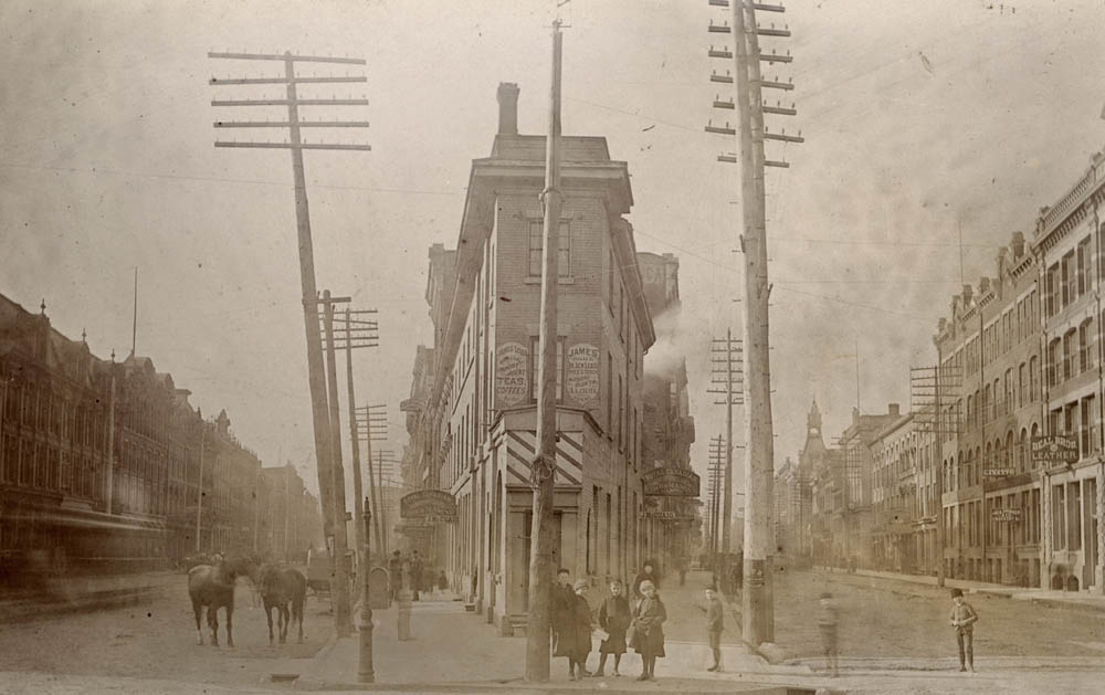 Boys stand in the street in front of the Coffin Block, a Front Street landmark built in a distinctive triangular shape.