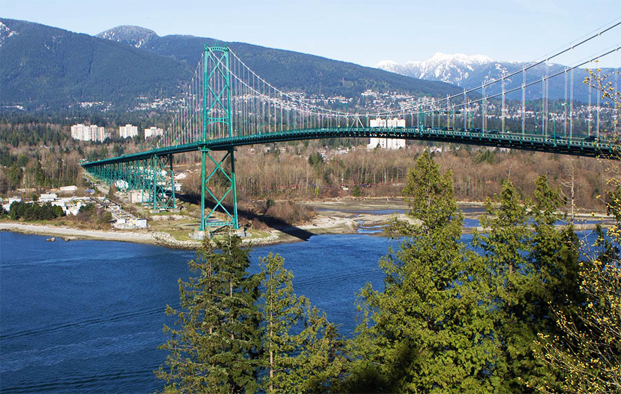 A small Union Steamship is passing under the Lions Gate Bridge during its construction. This view gives us a glimpse of North Vancouver which still appears almost entirely forested.